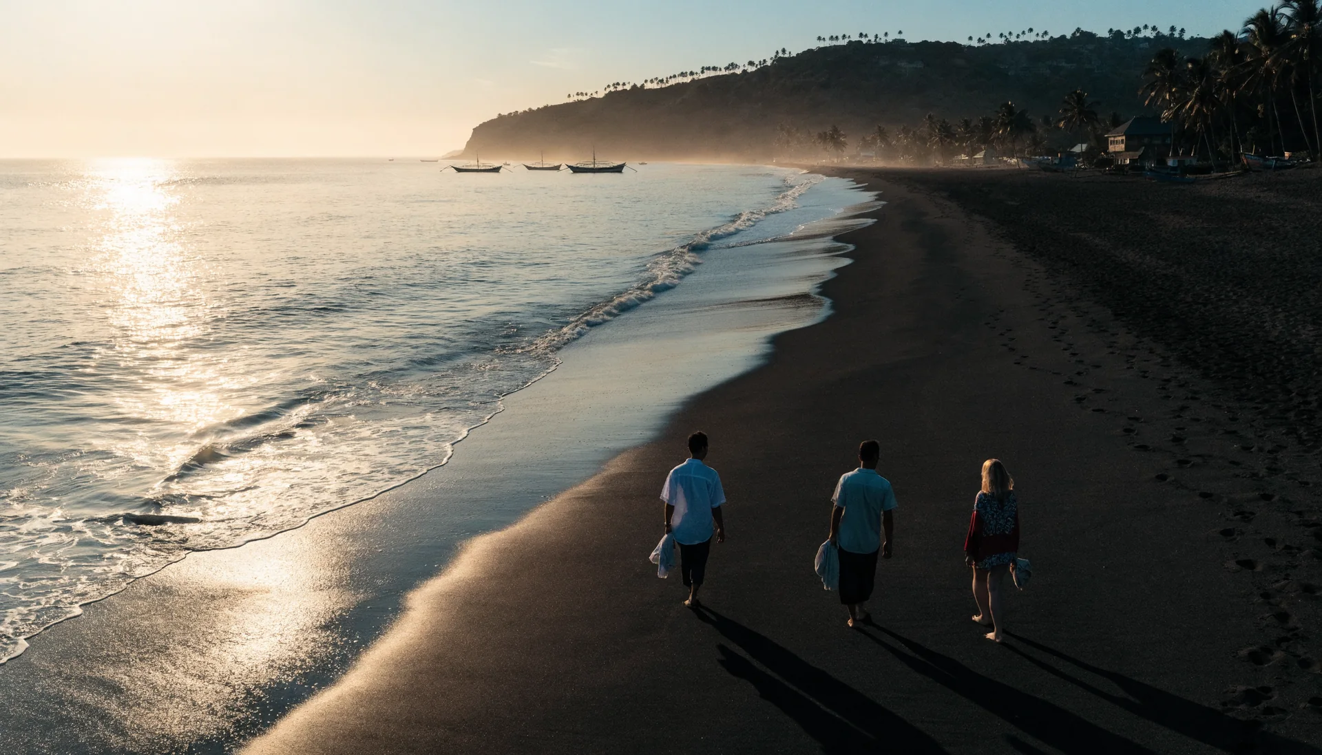 Three friends walking from behind along a black-sand Bali beach at sunset